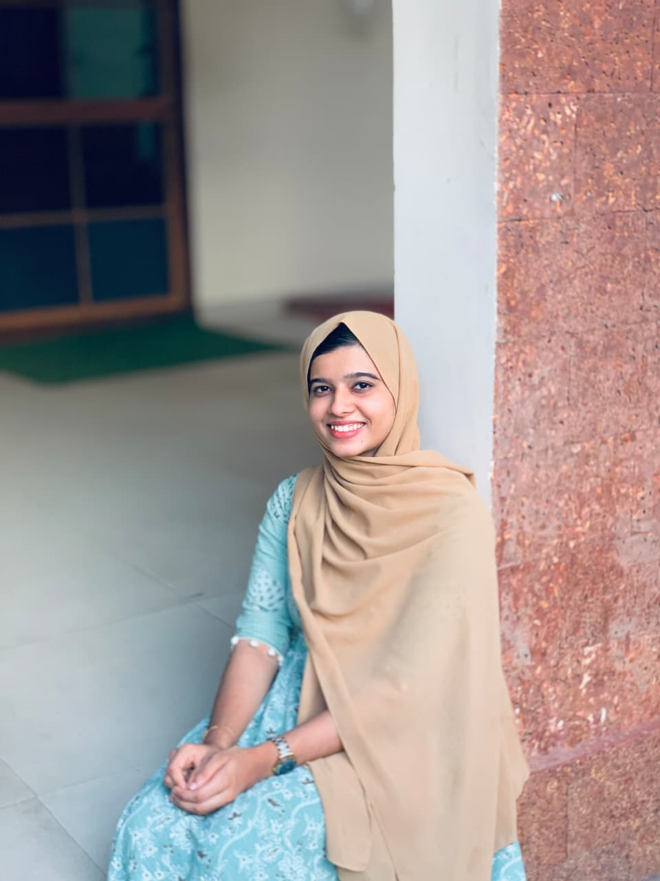 A woman in a hijab sits on the floor, representing a digital marketing freelancer in Kerala, focused and engaged in her work.